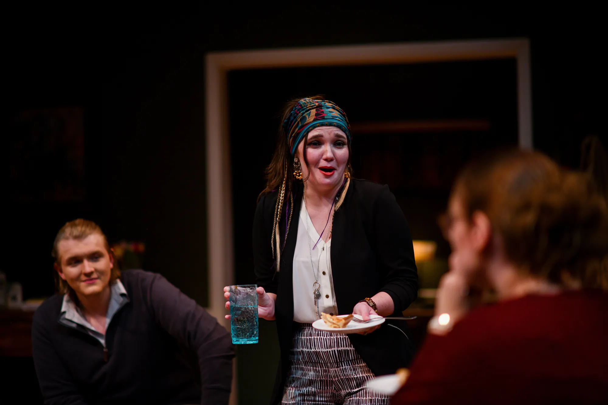 A woman in a headscarf laughs, plate in hand
