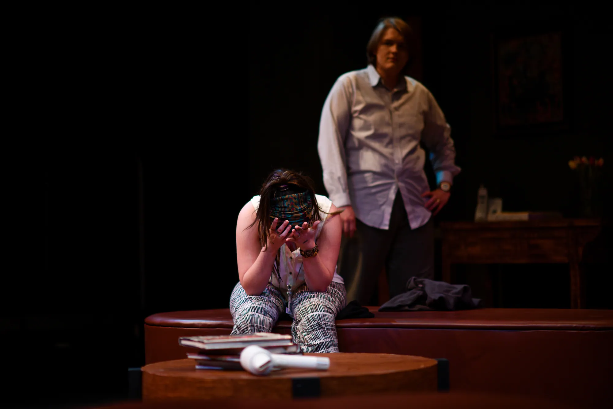A woman doubled over on the coffee table, a man standing behind her