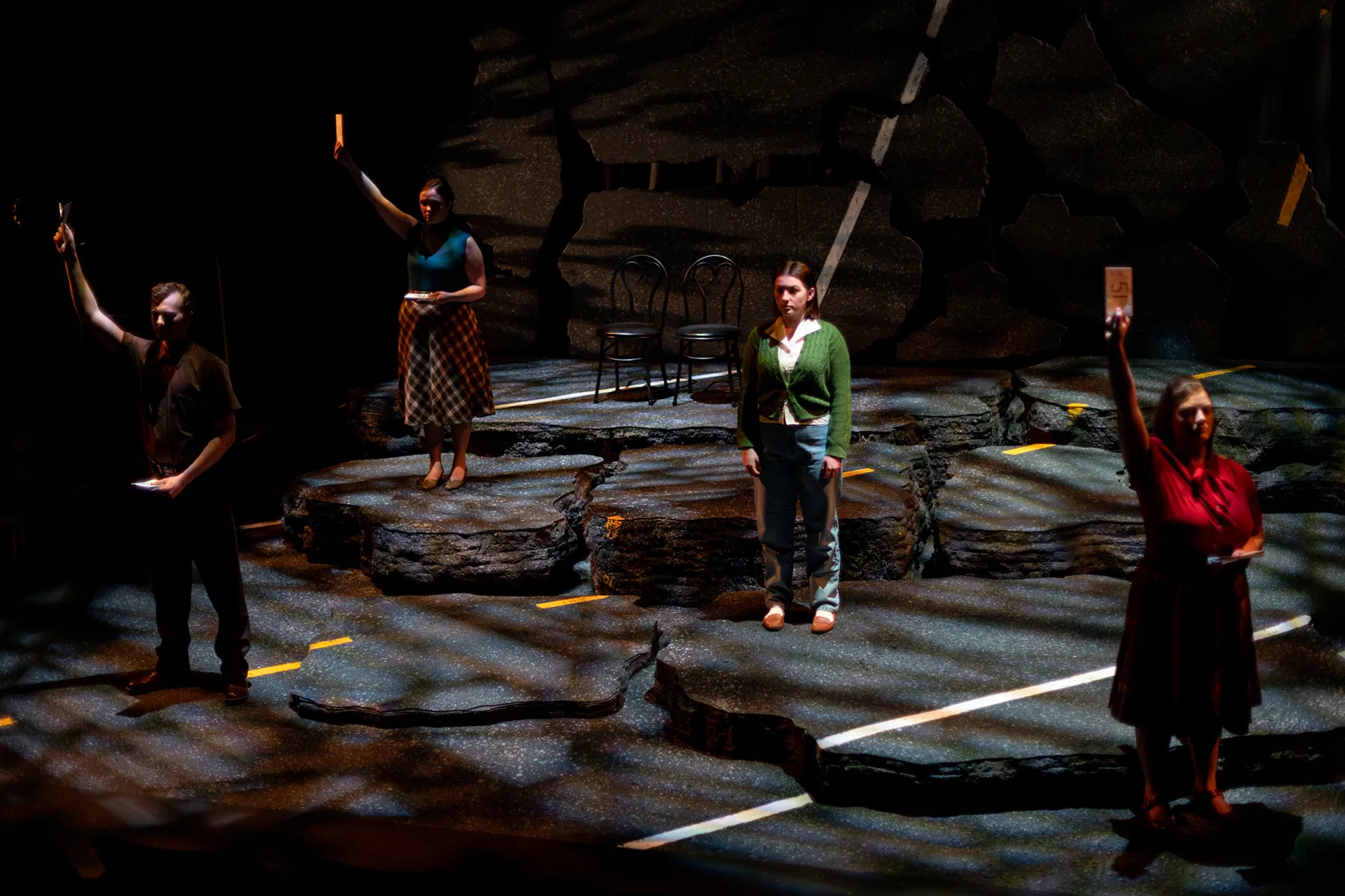 The ensemble raise their arms across the cracked highway set