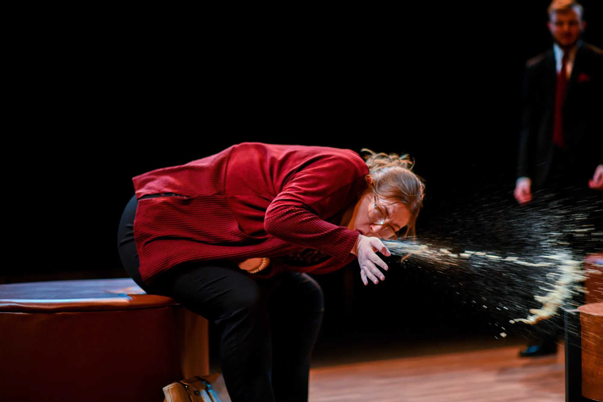 A woman in a red jacket is sick across the coffee table
