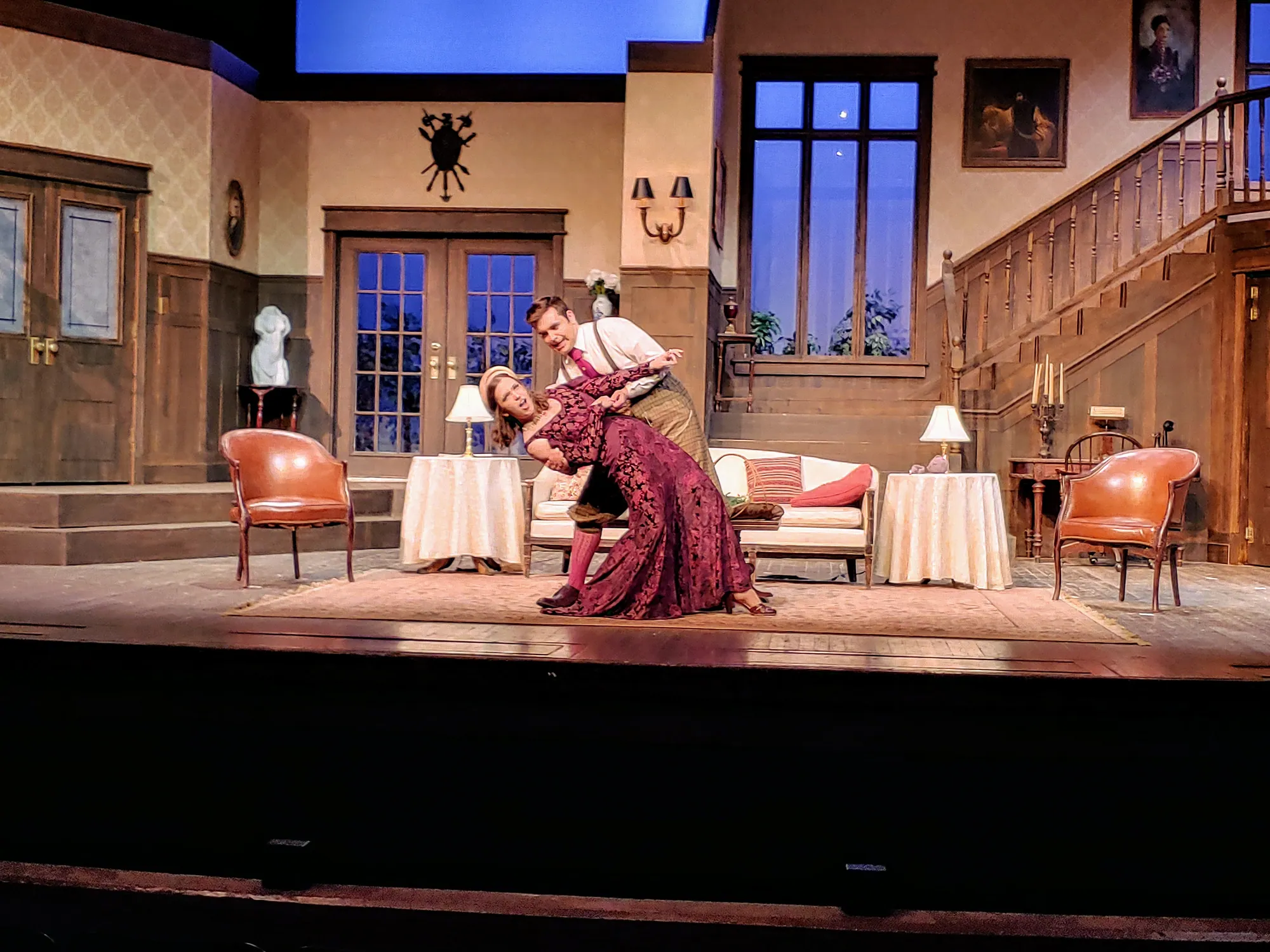 A man dips a woman in a dramatic embrace in the drawing room