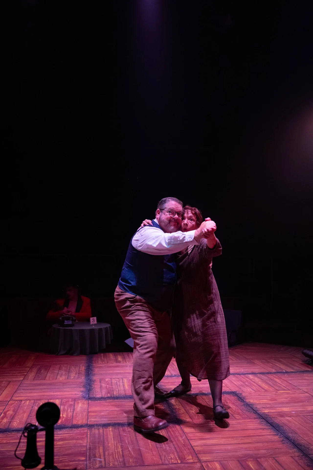 Jim Harris as Herr Schultz dancing cheek to cheek with a woman in a brown dress, grinning out at the audience