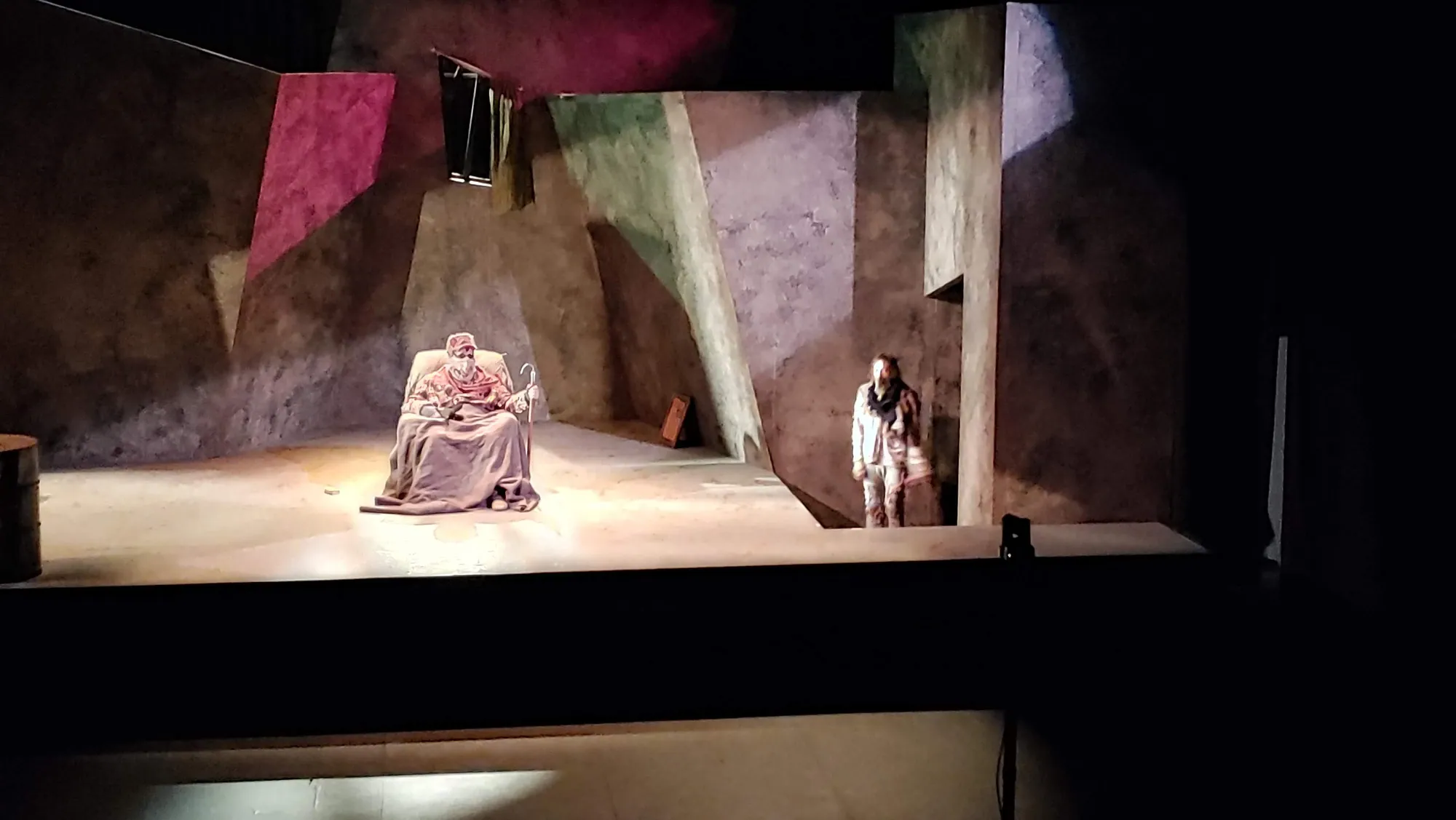 Hamm in his chair as Clov stands at the edge of the light