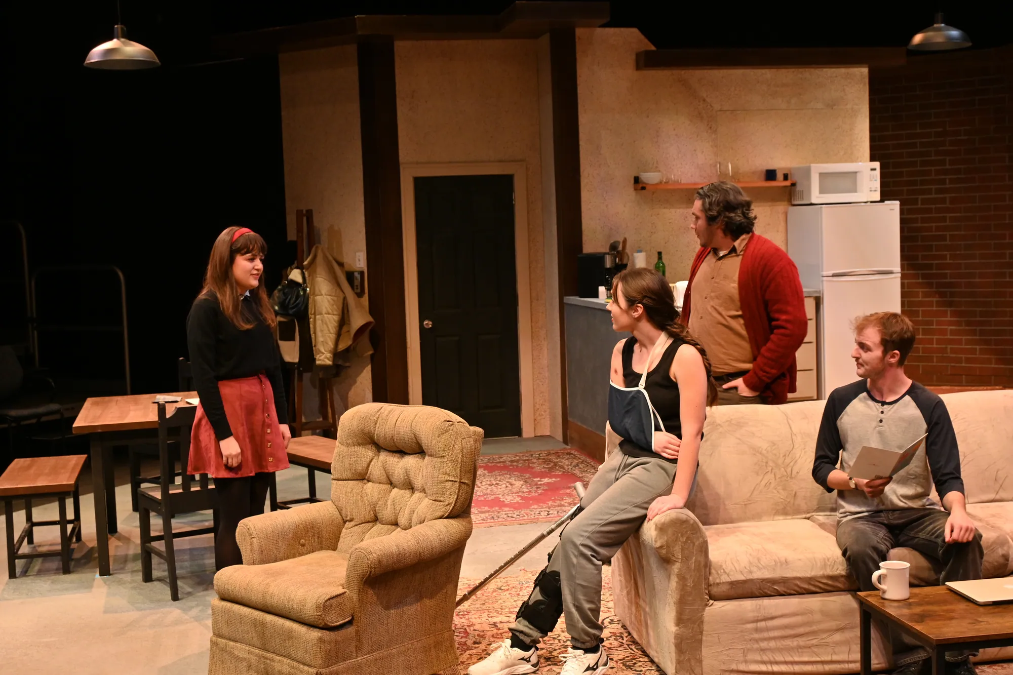 Five actors arranged around the living room of the loft