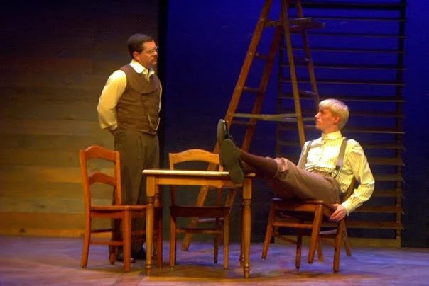 Jim Harris as Doc Gibbs in a waistcoat and watch chain, regarding a young man who leans back with his feet up on the kitchen table