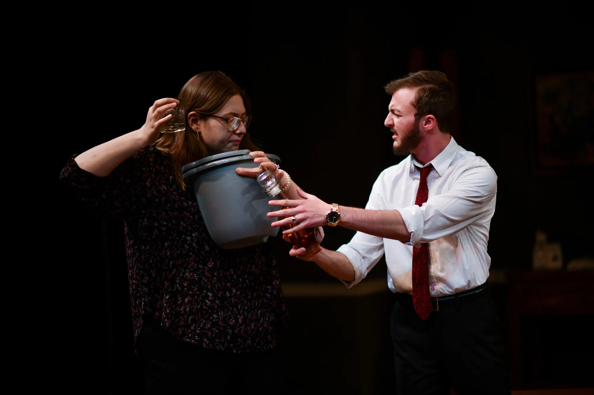A woman lifts a bucket as a man reaches toward her