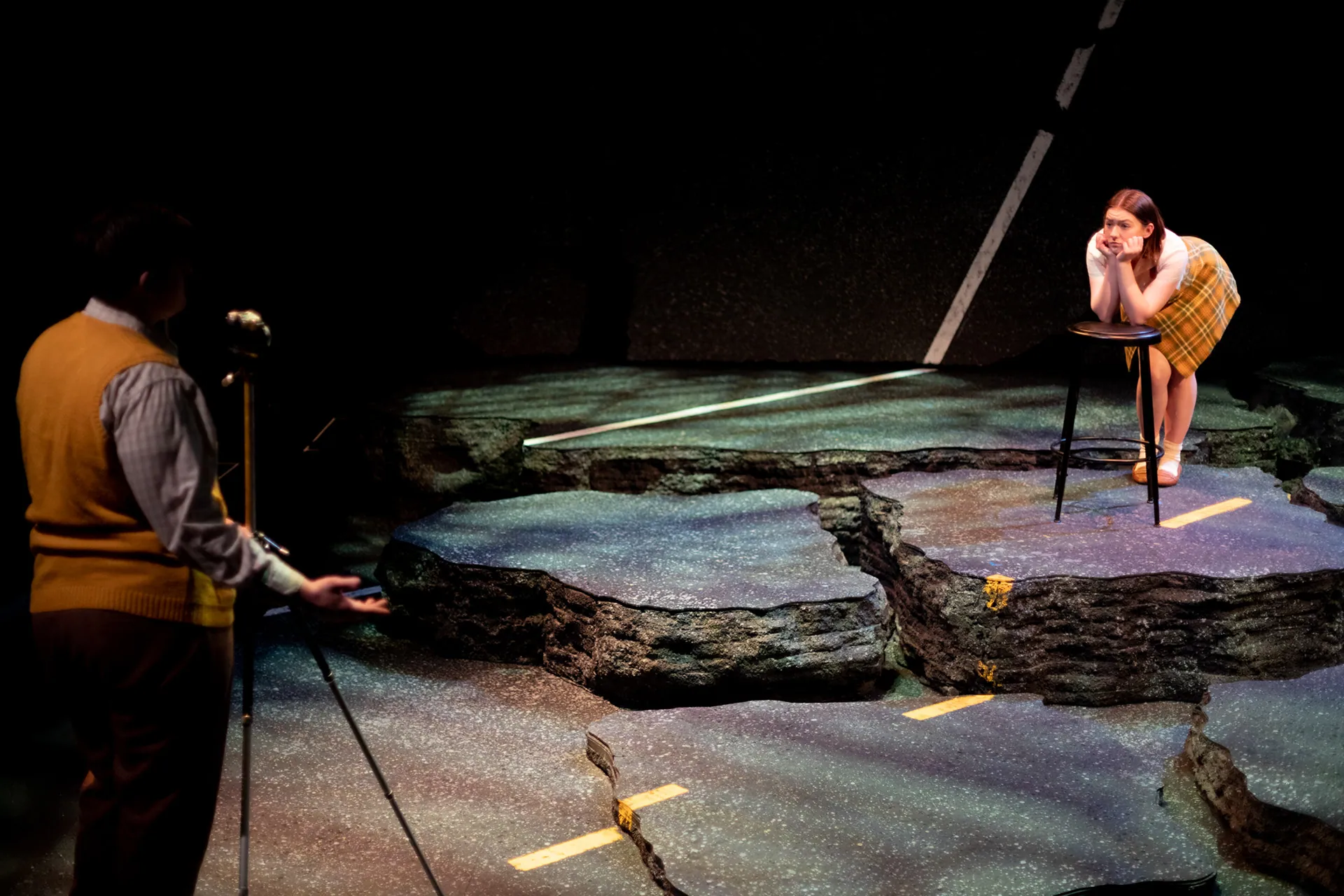 A woman perched on a rock while a man kneels in the foreground