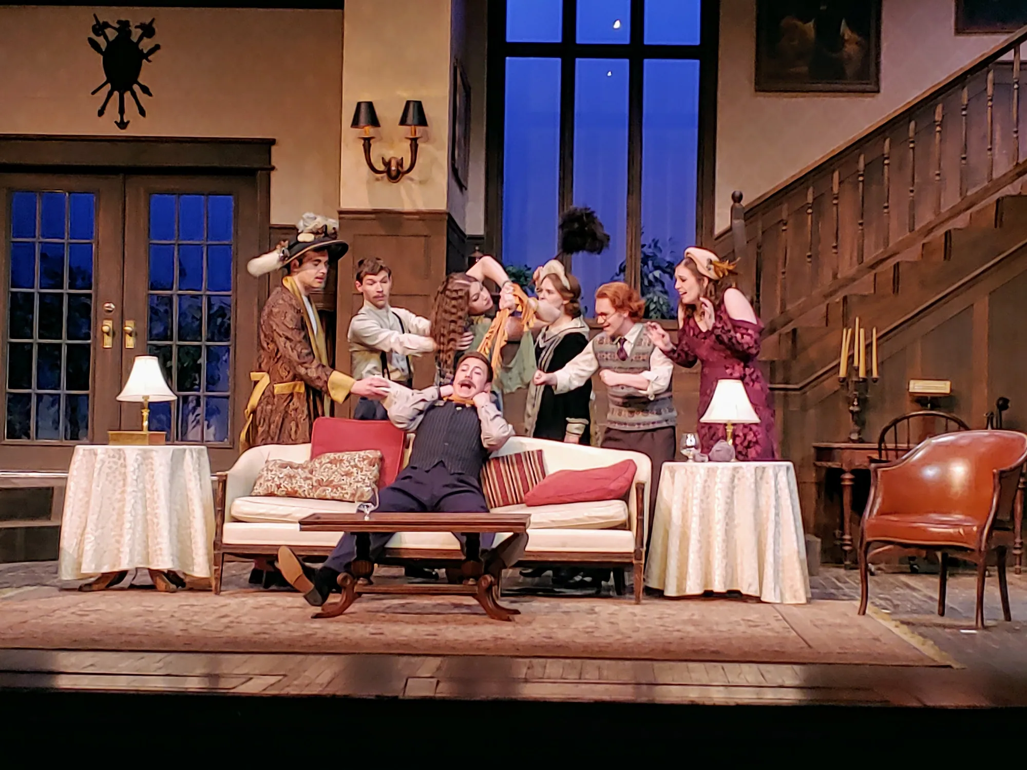 The company gathered around a man seated on the sofa