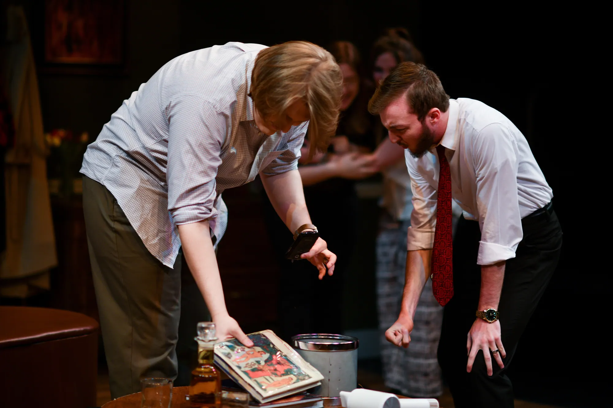 An actor bends to gather spilled art books